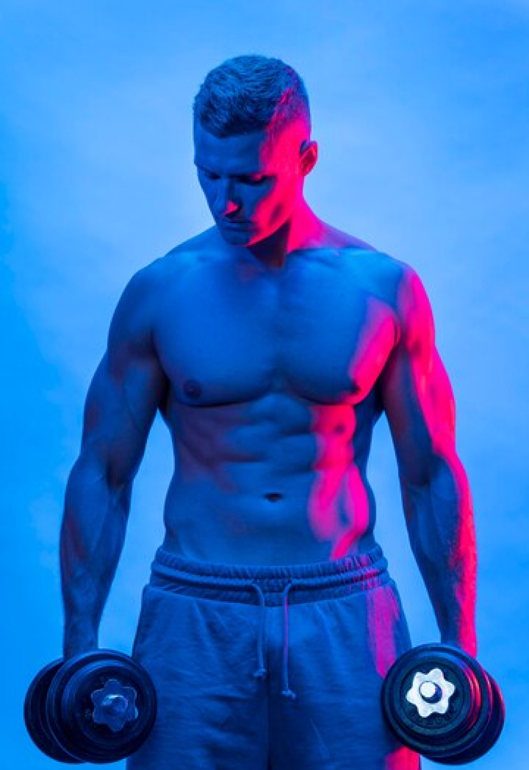 Спортивный мужчина держит в руках гантелю